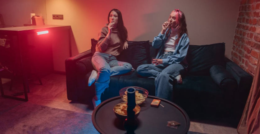 two women smoking on a couch
